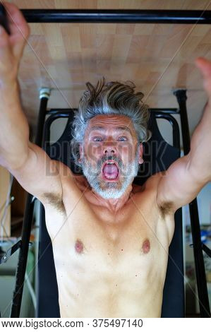 Mature Man Using Inversion Table At  Gym
