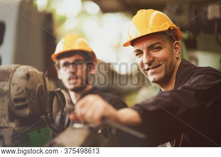 Scene Of Industrial Workers Wearing Jumpsuit And Yellow Safety Hat Turn His Face To Camera And Smile