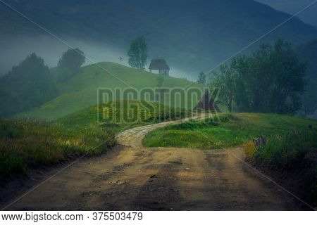 Two Old Abandoned Barn Houses On Top Of Hills On A Foggy Dramatic Day With A Road Leading To Them An