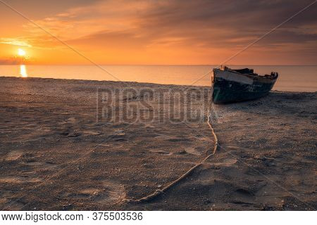 Low Perspective With A Rope Leading To A Fishing Boat On The Beach At Sunrise On The Black Sea Coast