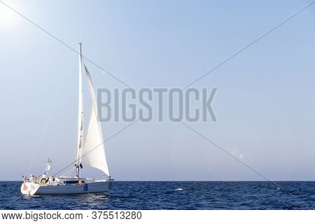 Sailboat With White Sails Under The Sun In Brittany