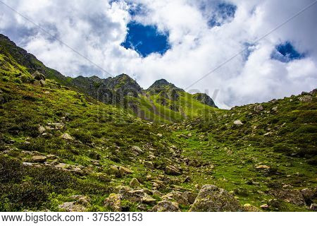 White Clouds, Blue Sky, Green Pastures And Spikes Of Granite Rock In The Lagorai In The Trentino Alp