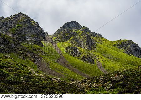 White Clouds, Blue Sky, Green Pastures And Spikes Of Granite Rock In The Lagorai In The Trentino Alp