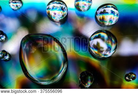 Drops Of Rain Water Are Falling On Cd Dix And Reflecting Sunlight. Yellow Blue And Red Light Is Bein