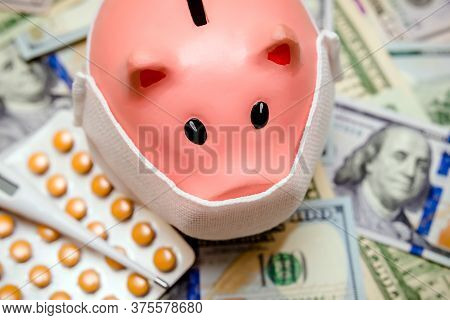 Piggy Bank In A Mask On A Background Of American Currency.the Concept Of Coronavrius Epidemic
