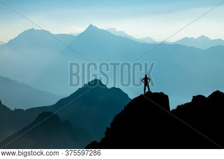 Man Reaching Summit After Climbing And Hiking Enjoying Freedom And Looking Towards Mountains Silhoue