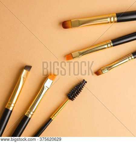 Set Of Gold And Black Brow Brushes Concept. Makeup Artists Brushes On An Isolated Background.