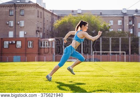 Young Professional Athlete Woman Practicing A Run On Stadium Green Grass On A Sunny Morning. Happy W