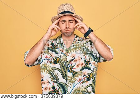 Young handsome man with blue eyes on vacation wearing summer florar shirt and hat suffering from headache desperate and stressed because pain and migraine. Hands on head.