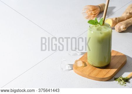 Iced Green Matcha Latte Tea With Ginger On White Table. Close Up.