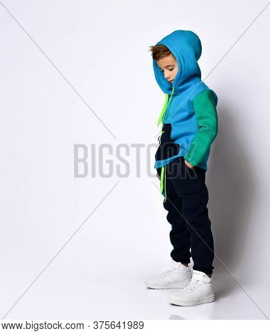 Side View Shot Of Little Schoolboy In Bright Cotton Tracksuit Standing With Hands In Pockets Looking