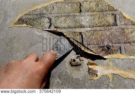 Hand With A Spatula Removes The Old Wallpaper Off The Wall, Repair The Home Premises.