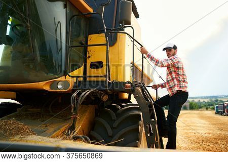 Harvester Machine Driver Climbing Into A Cab To Harvest His Wheat Field. Farmer Getting In Combine O