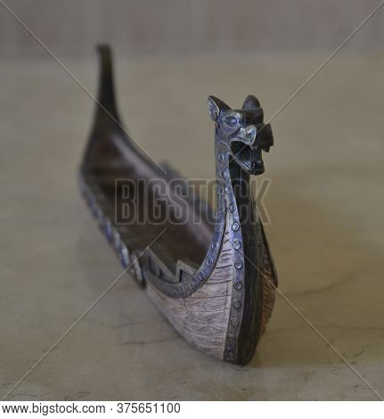 Censer. Incense holder made of resin in the shape of a Viking ship in front view on a travertine marble table