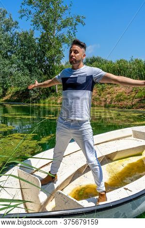 Young Man In White Pants And Modern Styling Posing In The Freshwater Pond Of Clot De La Mare De Deu 