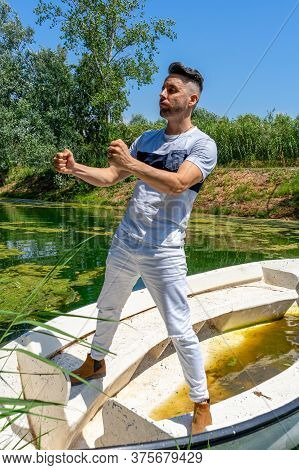 Young Man In White Pants And Modern Styling Posing In The Freshwater Pond Of Clot De La Mare De Deu 