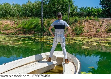 Young Man In White Pants And Modern Styling Posing In The Freshwater Pond Of Clot De La Mare De Deu 
