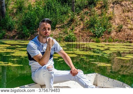 Young Man In White Pants And Modern Styling Posing In The Freshwater Pond Of Clot De La Mare De Deu 