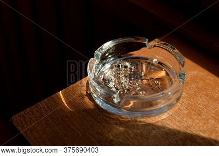Ashtray With A Cigarette Butt On Wooden Surface.
