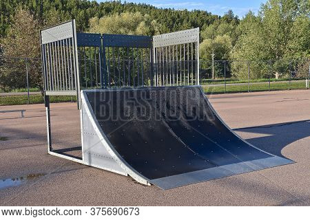 A Skateboard Park Features A Quarter Pipe For Skilled Skateboarders