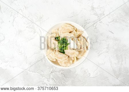 Dumplings With Sour Cream And Herbs In A Round, White Plate