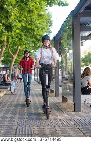 Trendy Fashinable Teenager Girls Riding Public Rental Electric Scooters In Urban City Environment. E