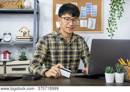 Asian Man Holding Credit Card And Typing Information On Internet With Laptop At Home, Online Shoppin