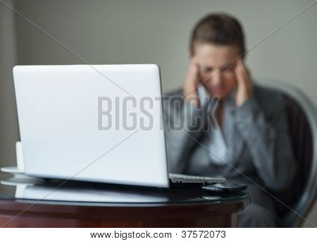 Detailní záběr na stůl s telefonem a Laptop a stresovaní obchodní žena v pozadí