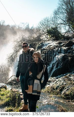Young Couple Standing And Posing Together In Nature At Kravice Watefalls In Bosnia, Cold River Water