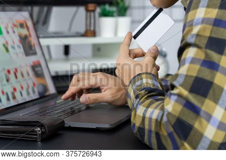 Asian Man Holding Credit Card And Typing Information On Internet With Laptop At Home, Online Shoppin