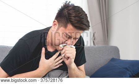 Asian Man With Seasonal Infections Cold Blowing His Nose And Sneezing Into Tissue With Headache Lyin