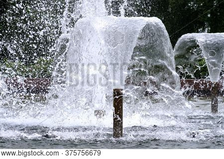 Selective Focus On Spray Of Urban Fountain And Blurred Background. A Fountain With Splashes And Drop