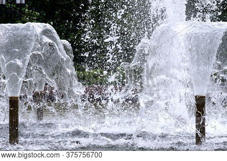 Selective Focus On Spray Of Urban Fountain And Blurred Background. A Fountain With Splashes And Drop