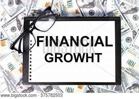 Financial Growht Text On White Paper On A Table On A Background Of Money And Glasses. Business Conce