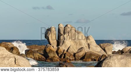 Huge Rock On A Beach In Aruba With Water Splashing Around It