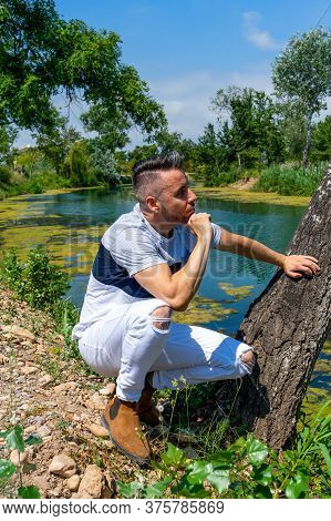Young Man In White Pants And Modern Styling Posing In The Freshwater Pond Of Clot De La Mare De Deu 
