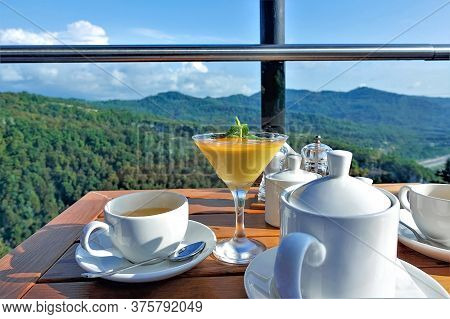 Tea Drinking In The Mountains On A Summer Sunny Day. On A Wooden Table Is A Teapot, Cups With Tea. I