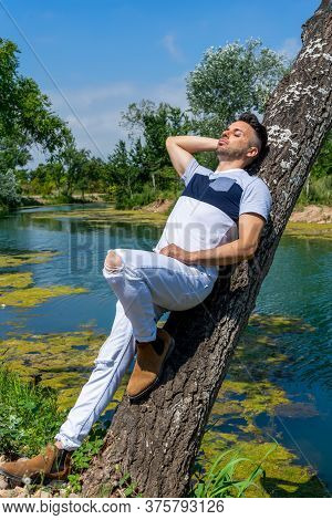 Young Man In White Pants And Modern Styling Posing In The Freshwater Pond Of Clot De La Mare De Deu 
