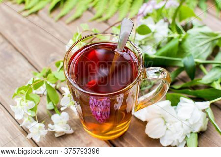 Green Tea Cup With Teaspoon And Floweer Buds On Old Wooden Table, With Copy Space. Summer Menu Conce
