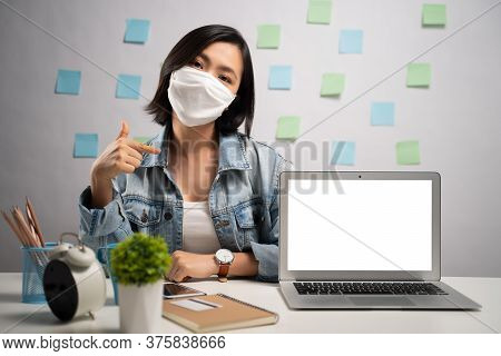 Asian Woman Wearing Protective Face Mask Showing Blank Screen At Home Office. Wfh. Work From Home. P
