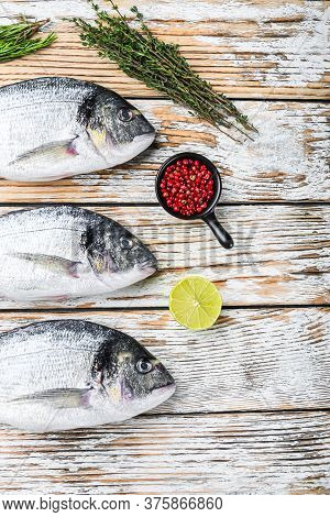 Whole Dorado Sea Bream Fish With Herbs For Grill Over White Wood Table Top View Space For Text.