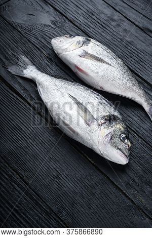 Raw Whole Pair  Dorado Or Sea Bream Fish Ob Black Wooden Table Side View.