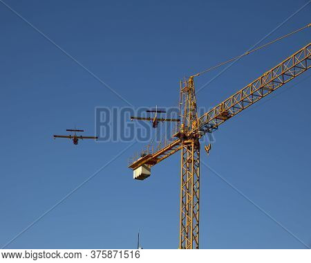La Coruña (spain), July 10, 2020. Two Firefighting Planes Fly Over A Crane. Forest Fires Are One Of 