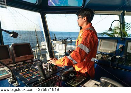 Filipino Deck Officer On Bridge Of Vessel Or Ship. He Is Speaking On Gmdss Vhf Radio