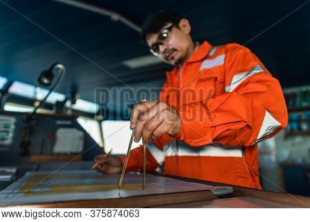 Filipino Deck Officer On Bridge Of Vessel Or Ship. He Is Plotting Position On Chart
