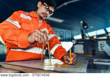 Filipino Deck Officer On Bridge Of Vessel Or Ship. He Is Plotting Position On Chart