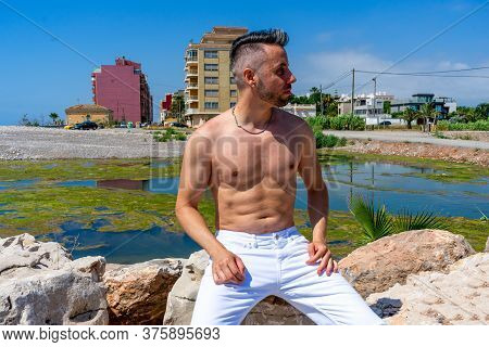Young Man In White Pants And Modern Styling Posing In The Freshwater Pond Of Clot De La Mare De Deu 