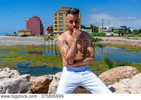 Young Man In White Pants And Modern Styling Posing In The Freshwater Pond Of Clot De La Mare De Deu 
