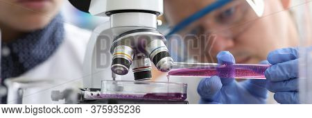 Man Pours Liquid Into Test Tube Under Microscope. Production Methods Drugs Are Constantly Being Impr