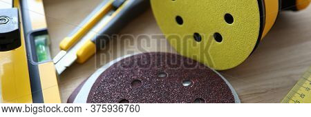 Close-up Of Bright Yellow Sander Machine And Replacement Discs On Wooden Table. Carpenters Essential